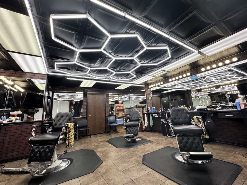 The barbering floor under the hexagon LED ceiling, chairs along the mirrors